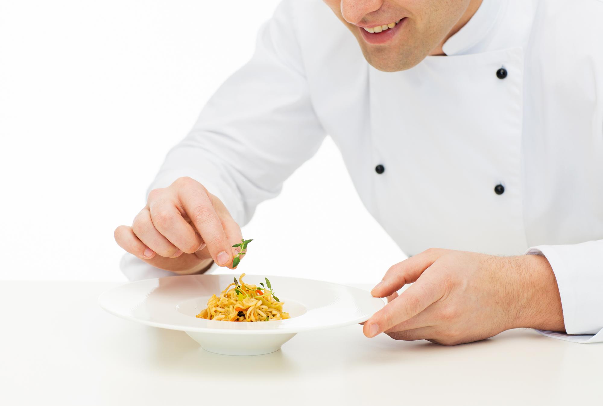 Chef arranging plated gourmet dish on wooden table